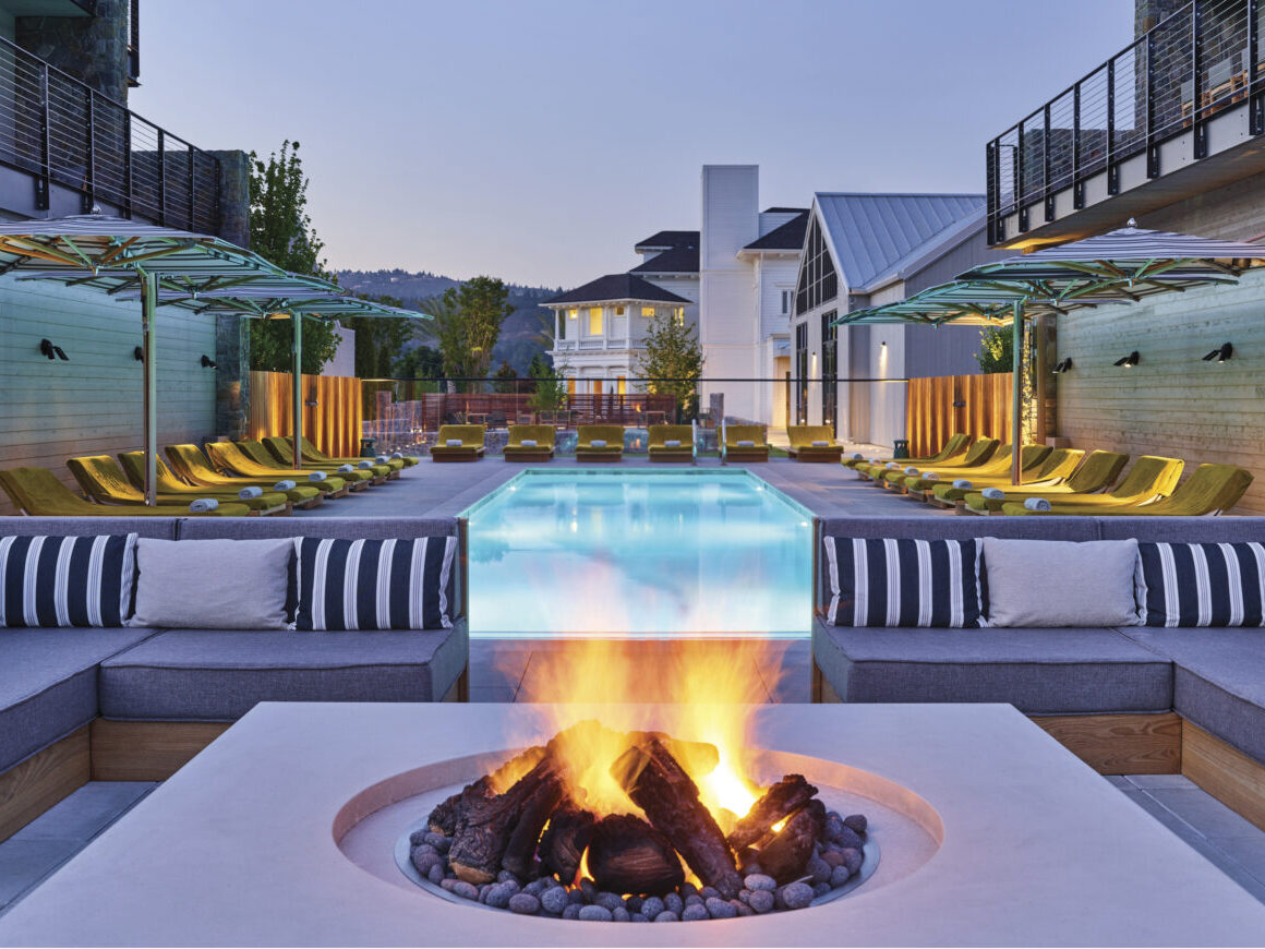 exterior patio with couches around fire pit with view of blue at dusk