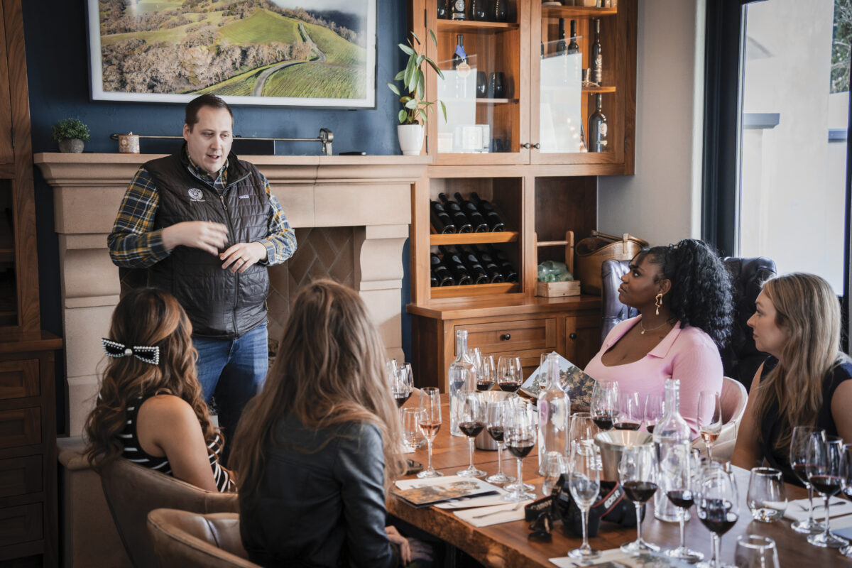 man standing, speaking to 3 women seated at table at Priest Ranch