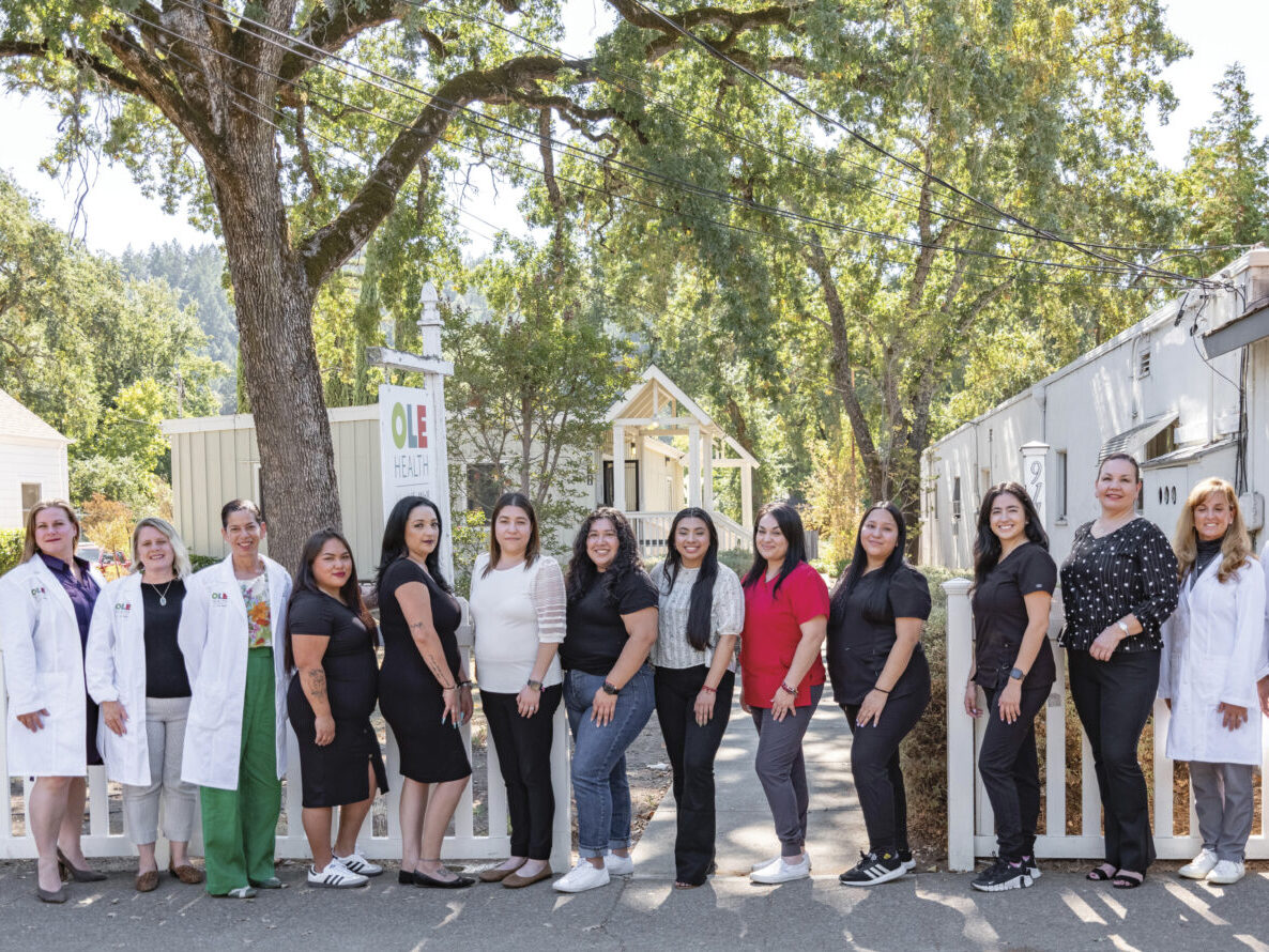 The Calistoga Team of OLE Health lined up outside of the office with trees around them