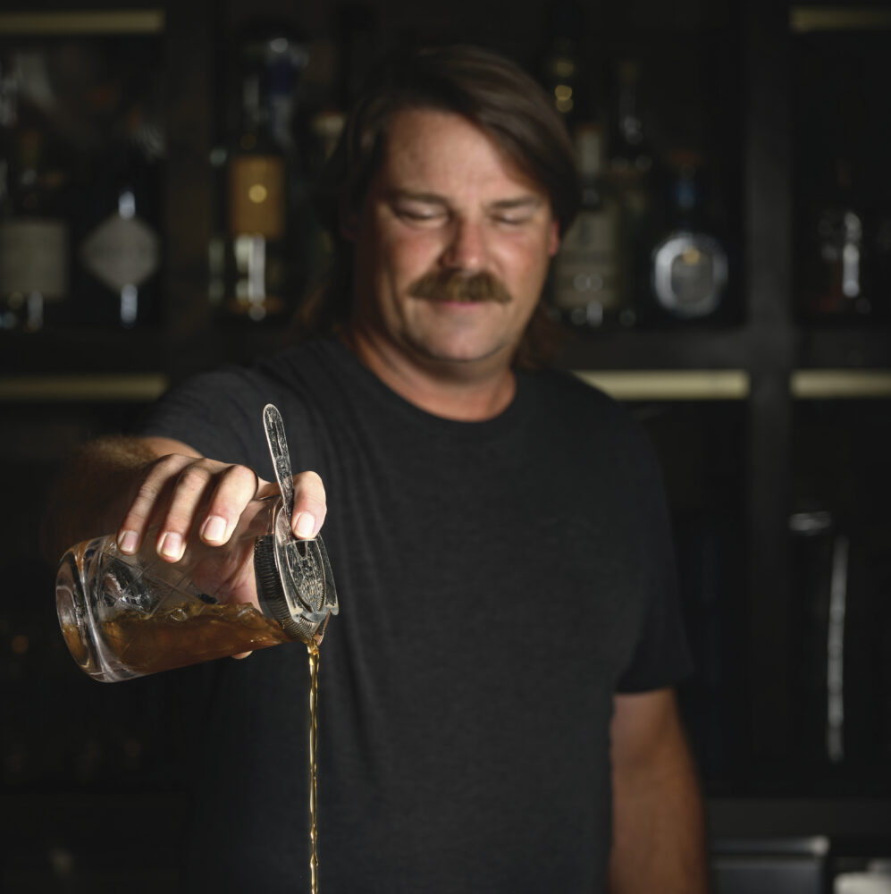 man with moustache pouring a drink at bar for the article Late Night Napa