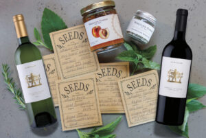 display of packets of seeds, jars of jams, bottles of wine with greenery on gray backgroun