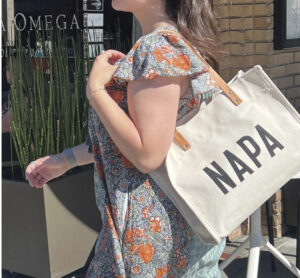 woman walking carrying bag with the word "Napa" on it for the article Holiday Gift Guide