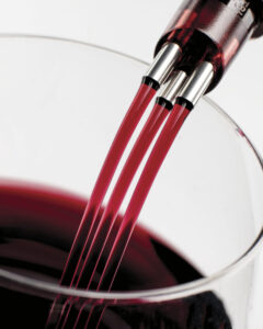 TRIbella wine aerator with red wine filtering through into a wine glass with white background