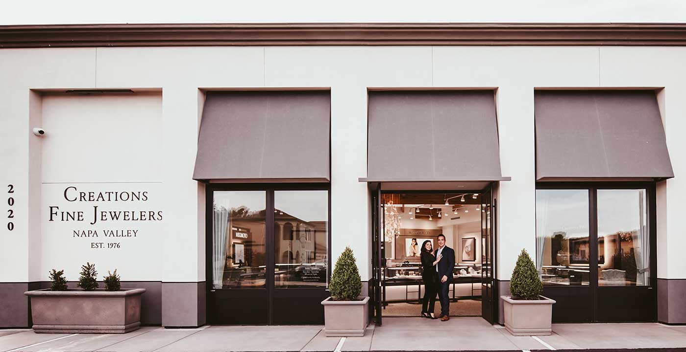 Creations Fine Jewelers owners Melissa and Brian Doughty standing in front of their storefront exterior