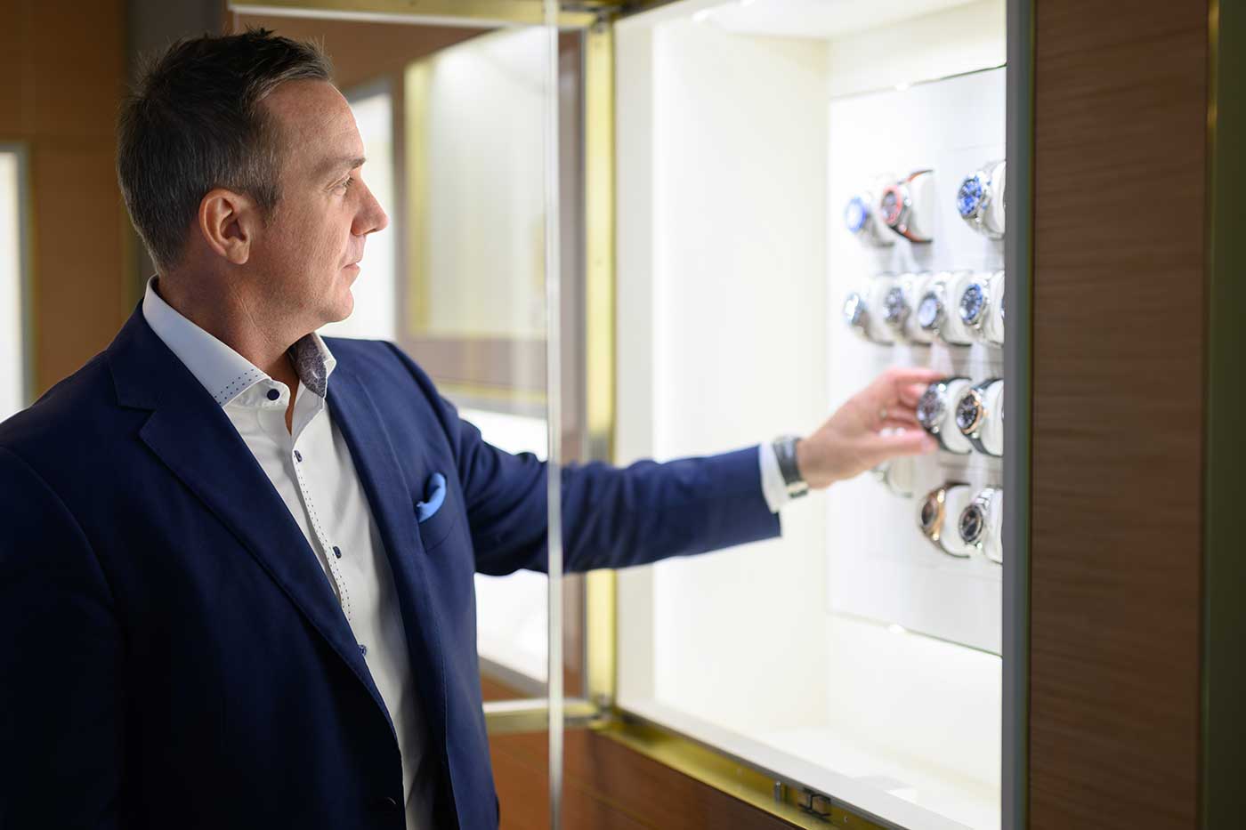 Creations Fine Jewelers co-owner Brian Doughty looking at a display of watches in case