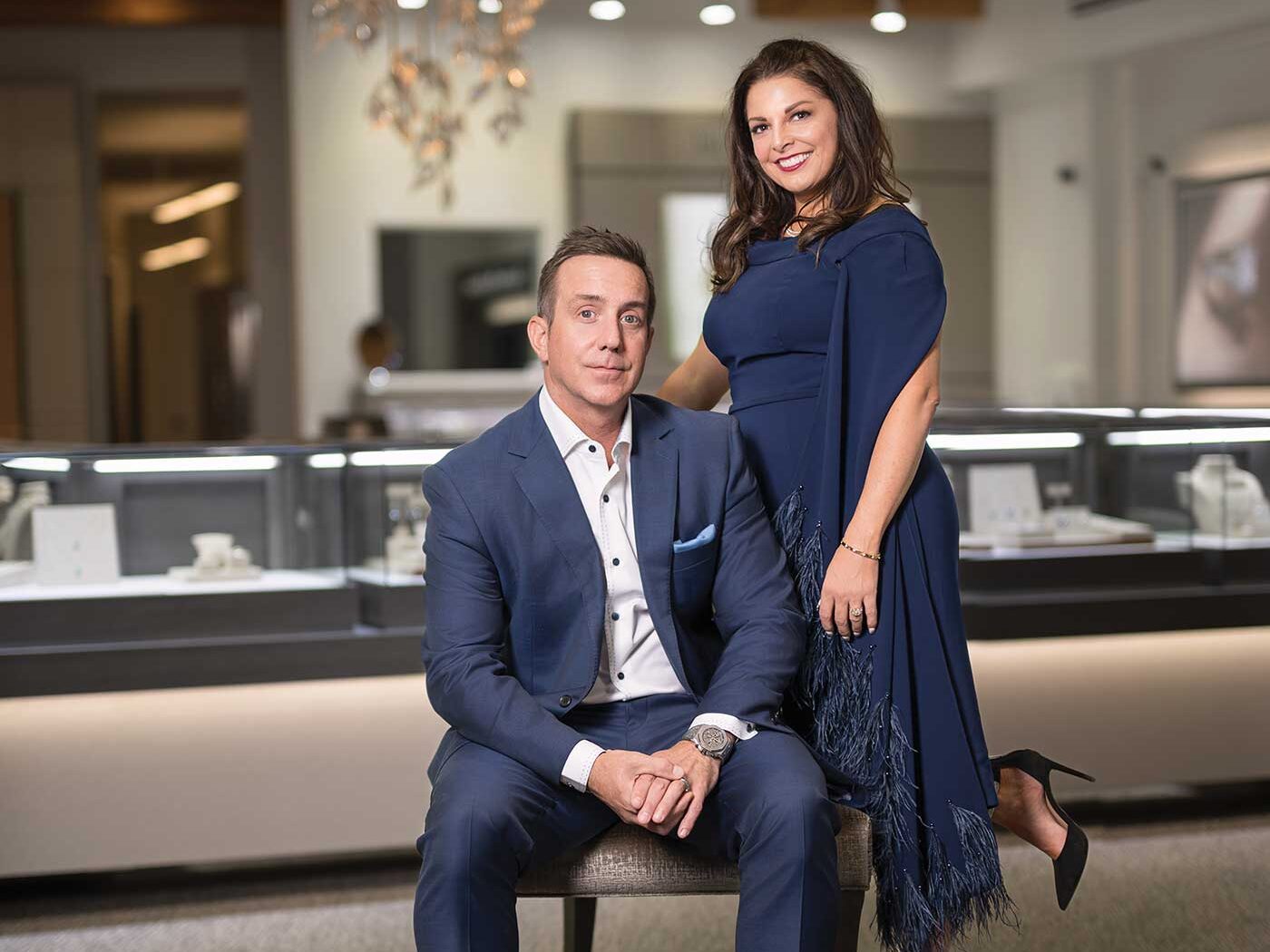 Creations Fine Jewelers owners Melissa (standing wearing navy dress, smiling) and Brian Doughty (seated, wearing navy suit) in their newly remodeled store in Napa Valley