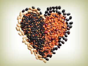 different colored raw beans in the shape of a heart on white background for the new year article