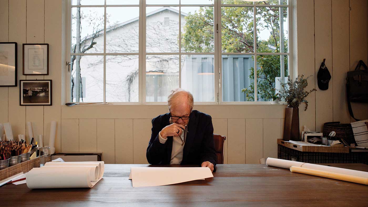 Howard J. Backen seated at desk looking down at paper with window behind