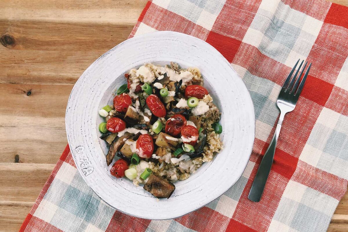 white bowl with grains and vegetables on red and white checkered tablecloth for the new year article