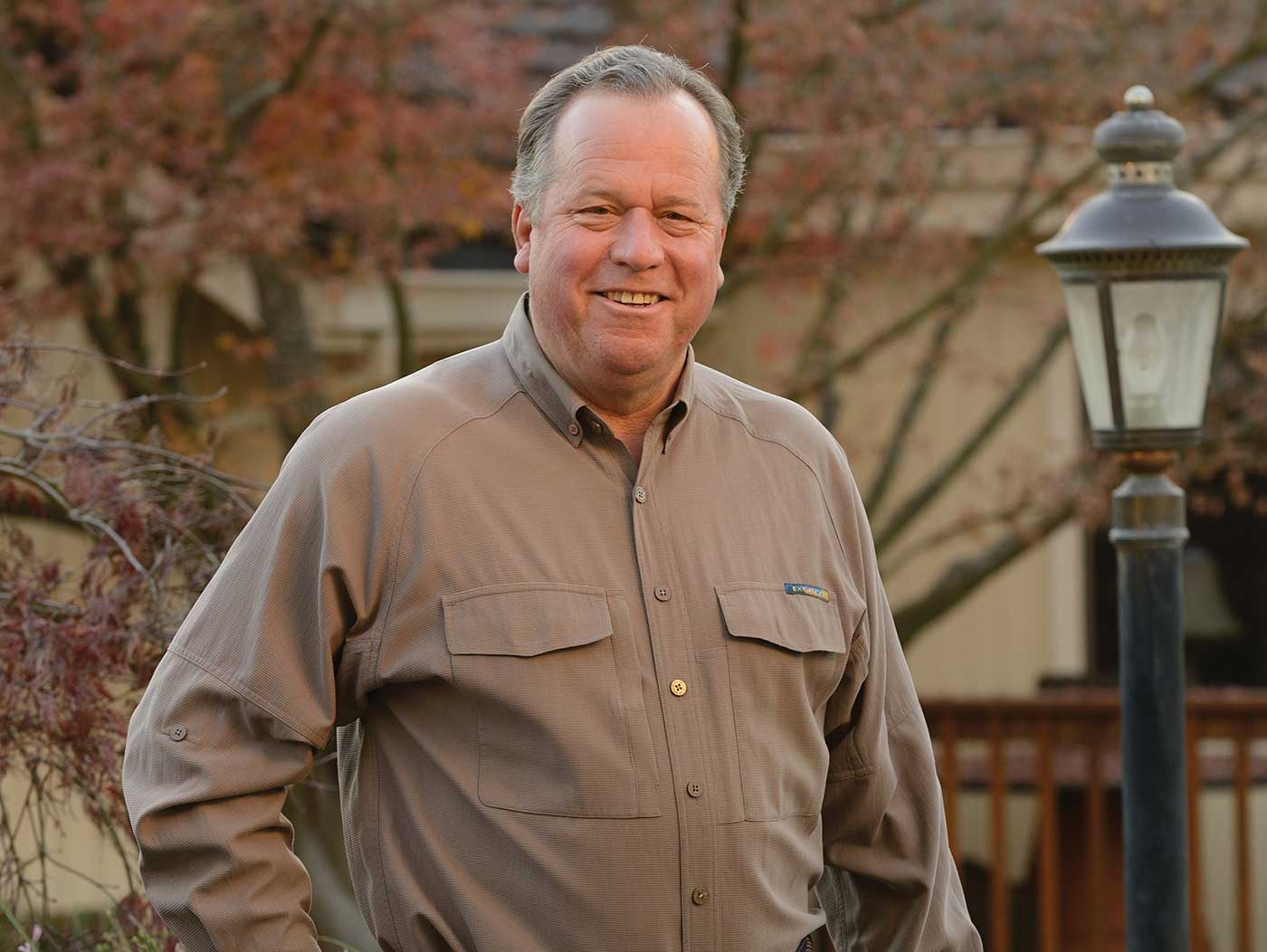 Bill Dodd standing outside in tan shirt near lightpost, smiling