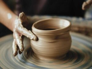 person's hand making pottery on pottery wheel for inner artist article