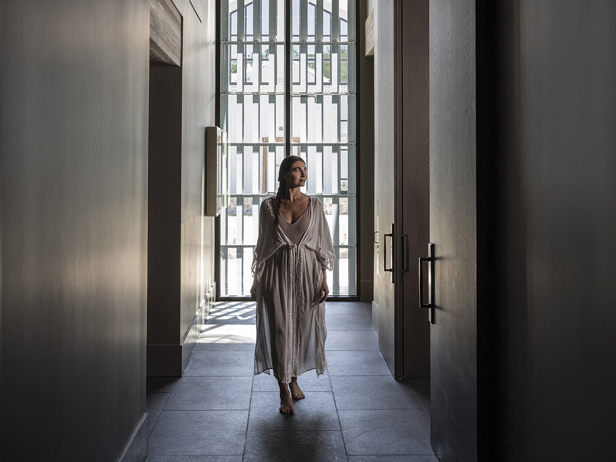 Spa-Alila woman in robe walking down hallway with windows in background at Spa Alila for Health and Wellness article