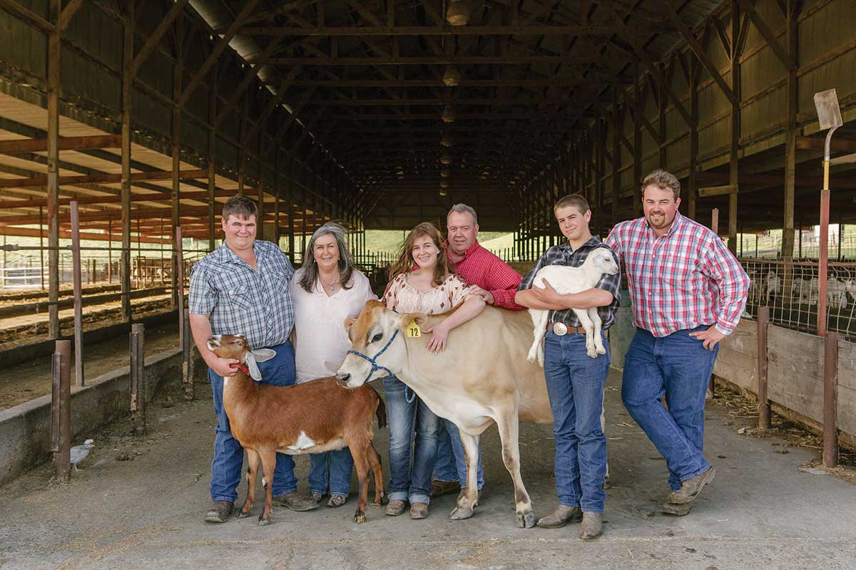 The Pacheco Family in barn with 2 cows for the Cheese Trail article. photo courtesy of Achadinha Farm