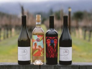 4 bottles of wine on an outdoor ledge with vineyards in the background for Clif Family Winery & Farm article