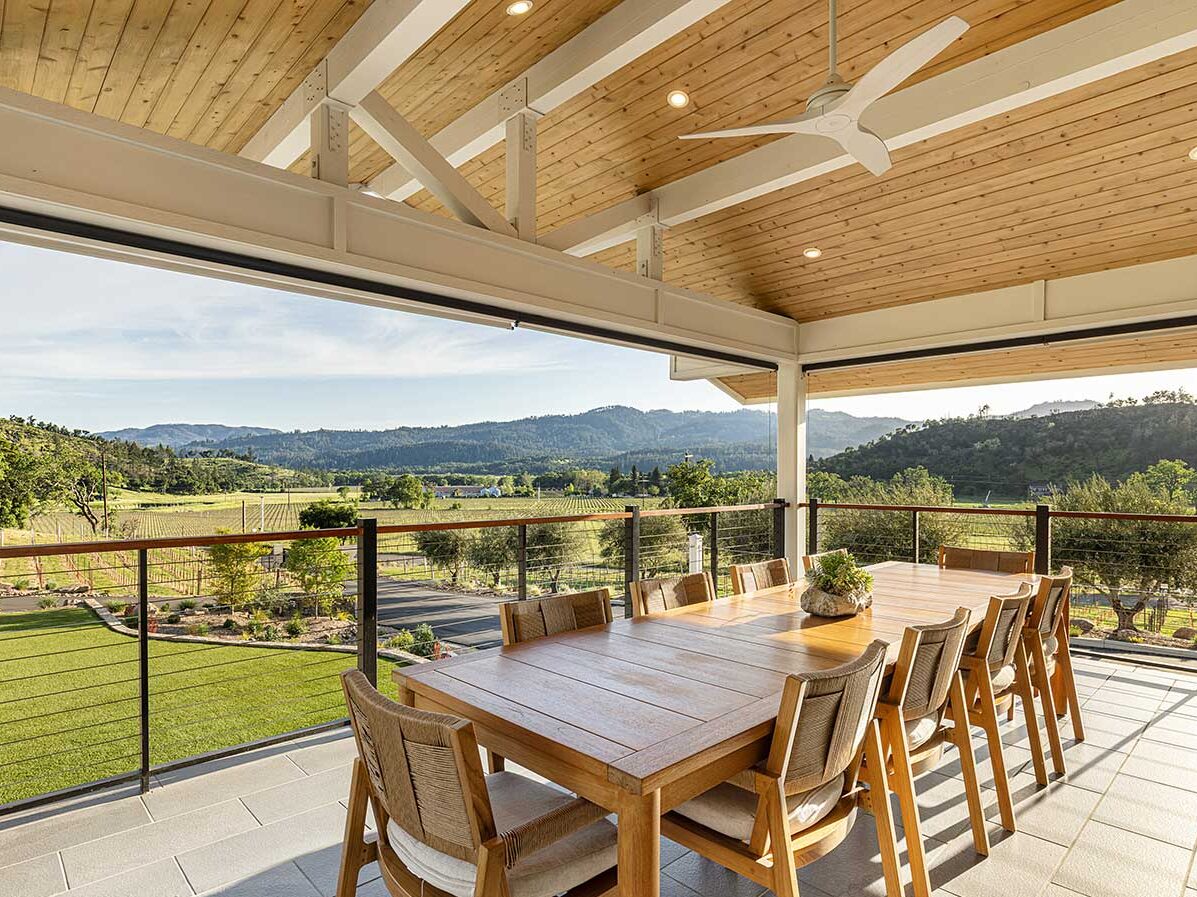 view of Reverie Winery Estate vineyards from outdoor porcj of winery with wood table and chairs in view