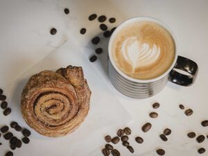 latte, cinnamon roll with coffee beans on table for Sam's General Store article