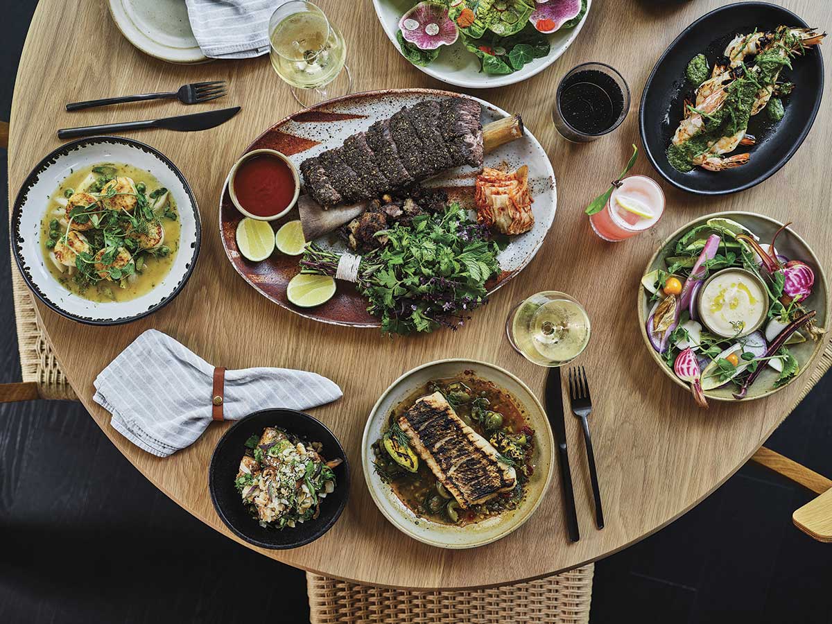 aerial view of round wooden table with various dishes and glasses at the restaurant Bear at Stanly Ranch in Napa Valley for the Napa Valley Restaurant Month article